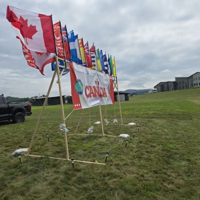 Flags on a grassy field with Canadian flags and promotional banners.