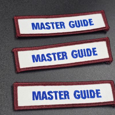 Three rectangular embroidered patches with maroon borders and white backgrounds, each reading 